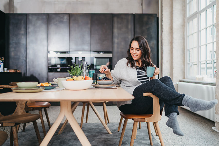 Frau sitzt entspannt in einer großen modernen Küche